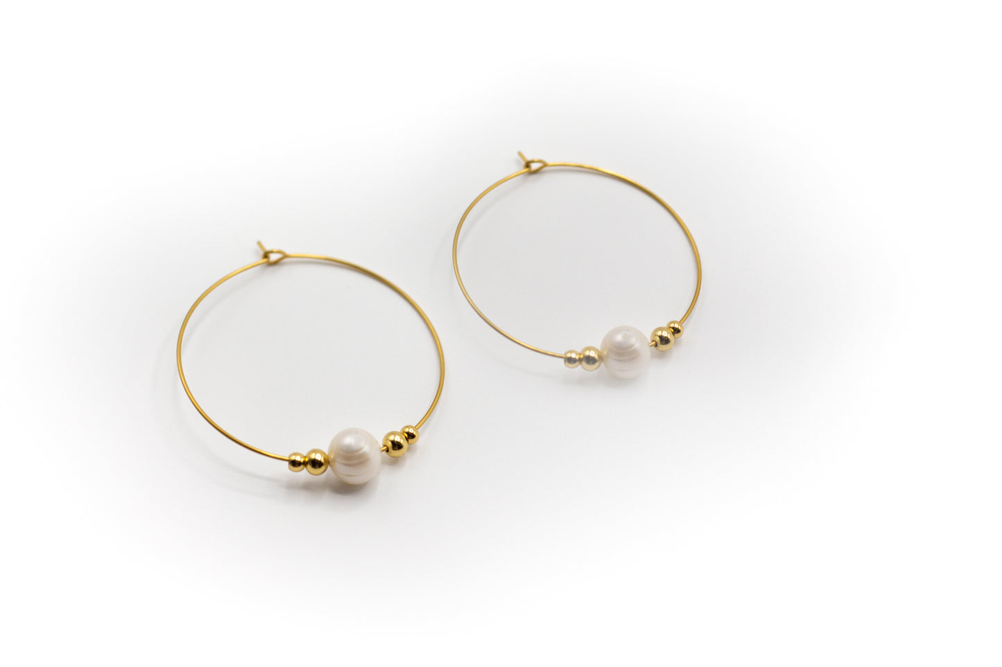 Goldfarbene Creolen aus Edelstahl mit Naturperle