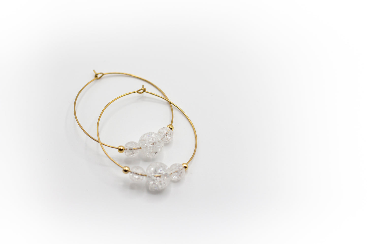 Goldfarbene Creolen aus Edelstahl mit natürlichem, rissigem weißem Quarzstein